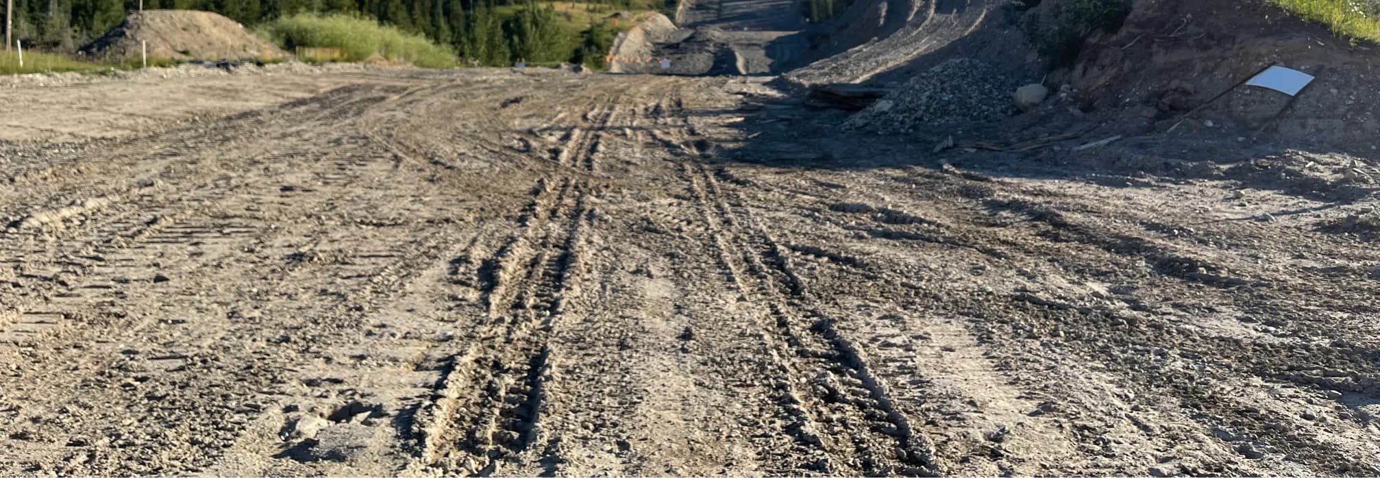 Stripped and cleared access route across a work site showing equipment tracks through native ground