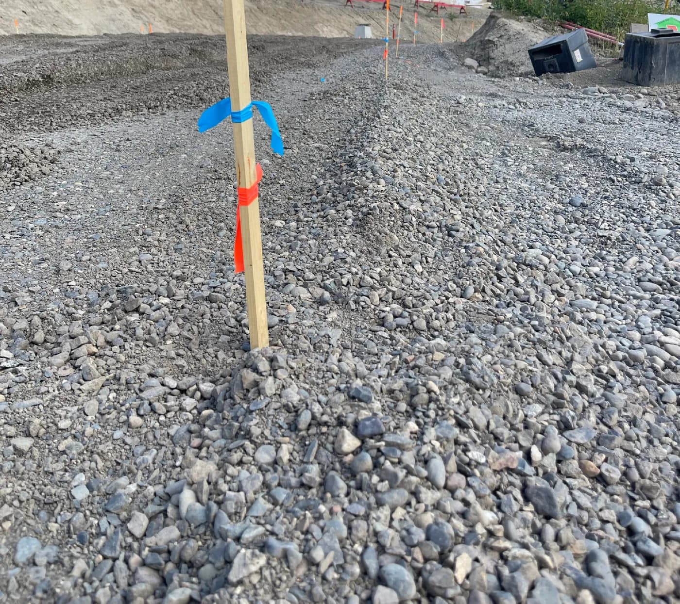 Crushed gravel road base placed to grade stakes with flagging on a construction site