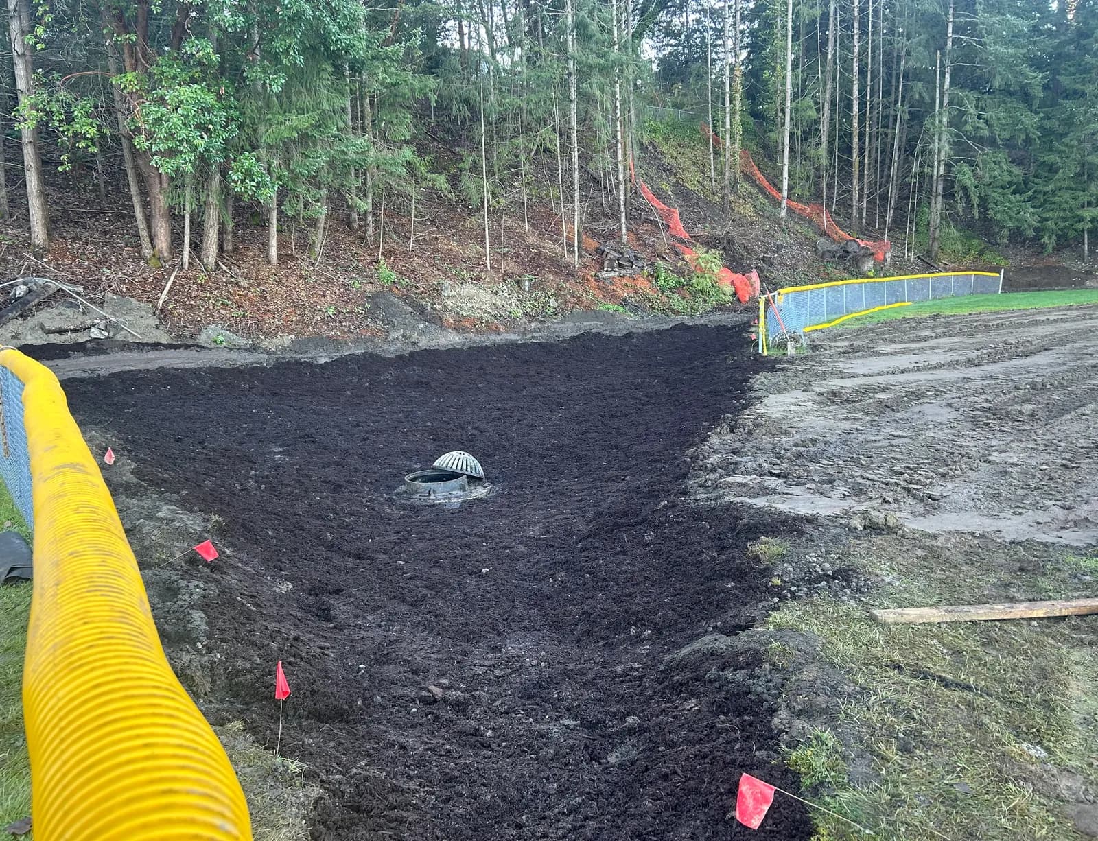 New catch basin set in a graded drainage swale with corrugated drain pipe and sediment control fencing on a forested Campbell River site
