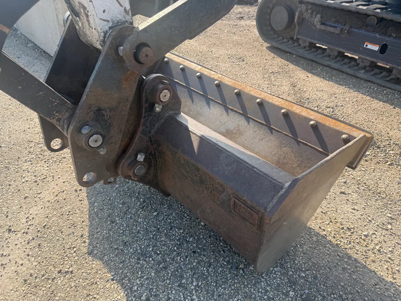 Close-up of an excavator bucket and quick-coupler on a compact excavator