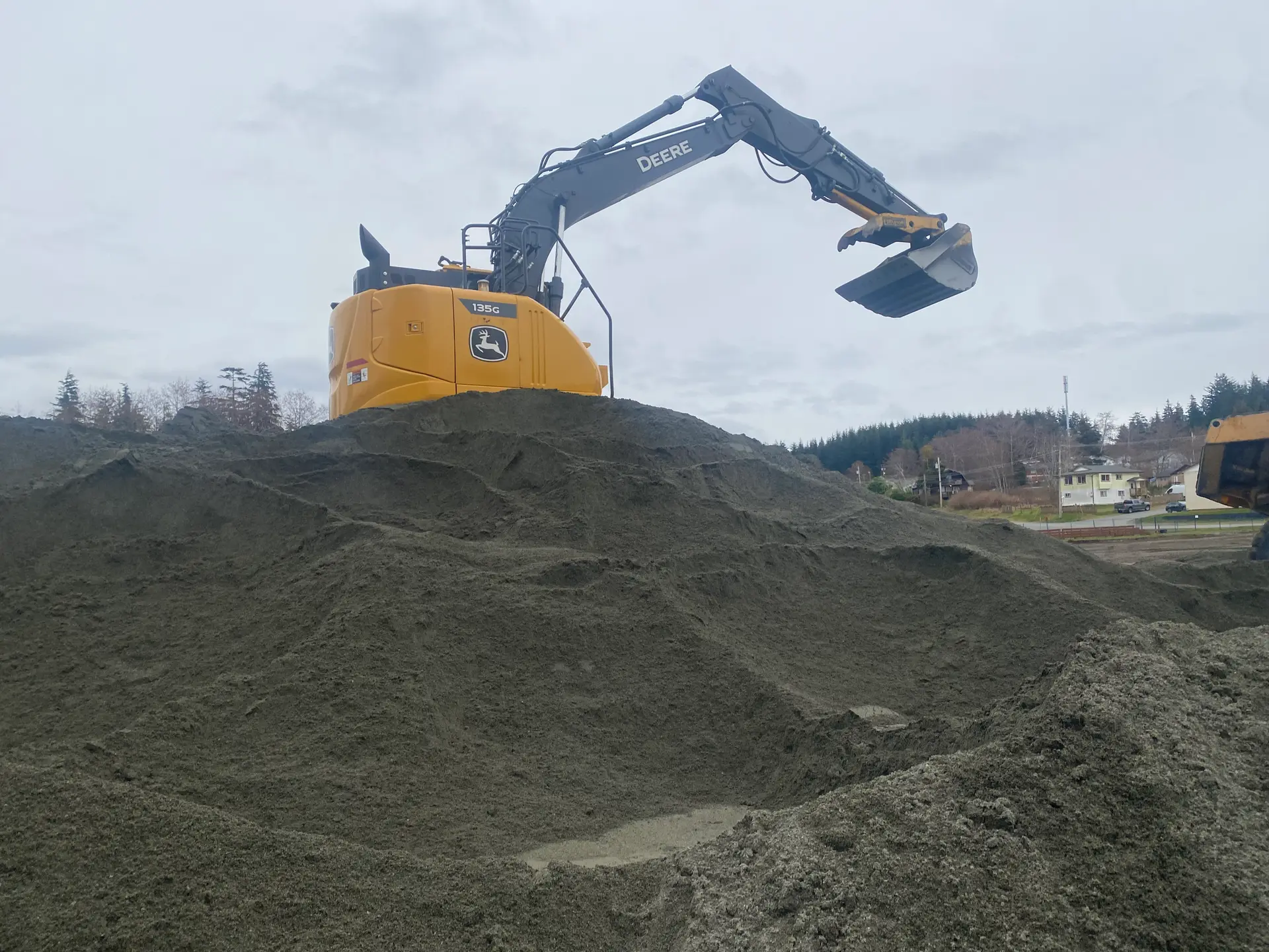 Excavator on a stockpile of clean granular material used for drainage and backfill behind retaining walls