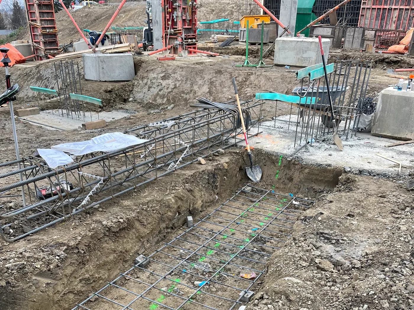 Reinforced footing cage in an open excavation with green survey layout marks along the trench line