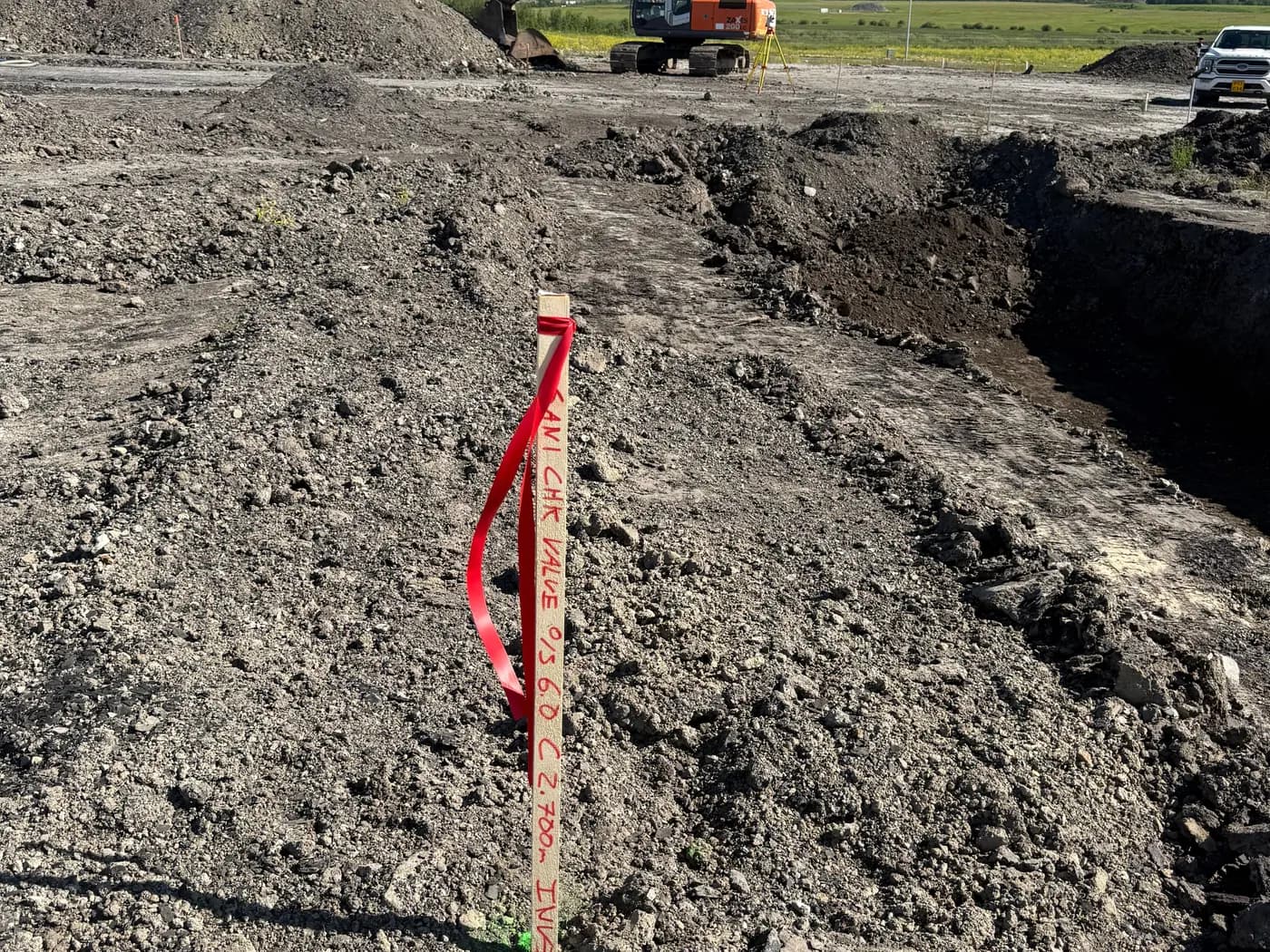 Surveyed grade stake with marking ribbon set in an excavation area during site construction