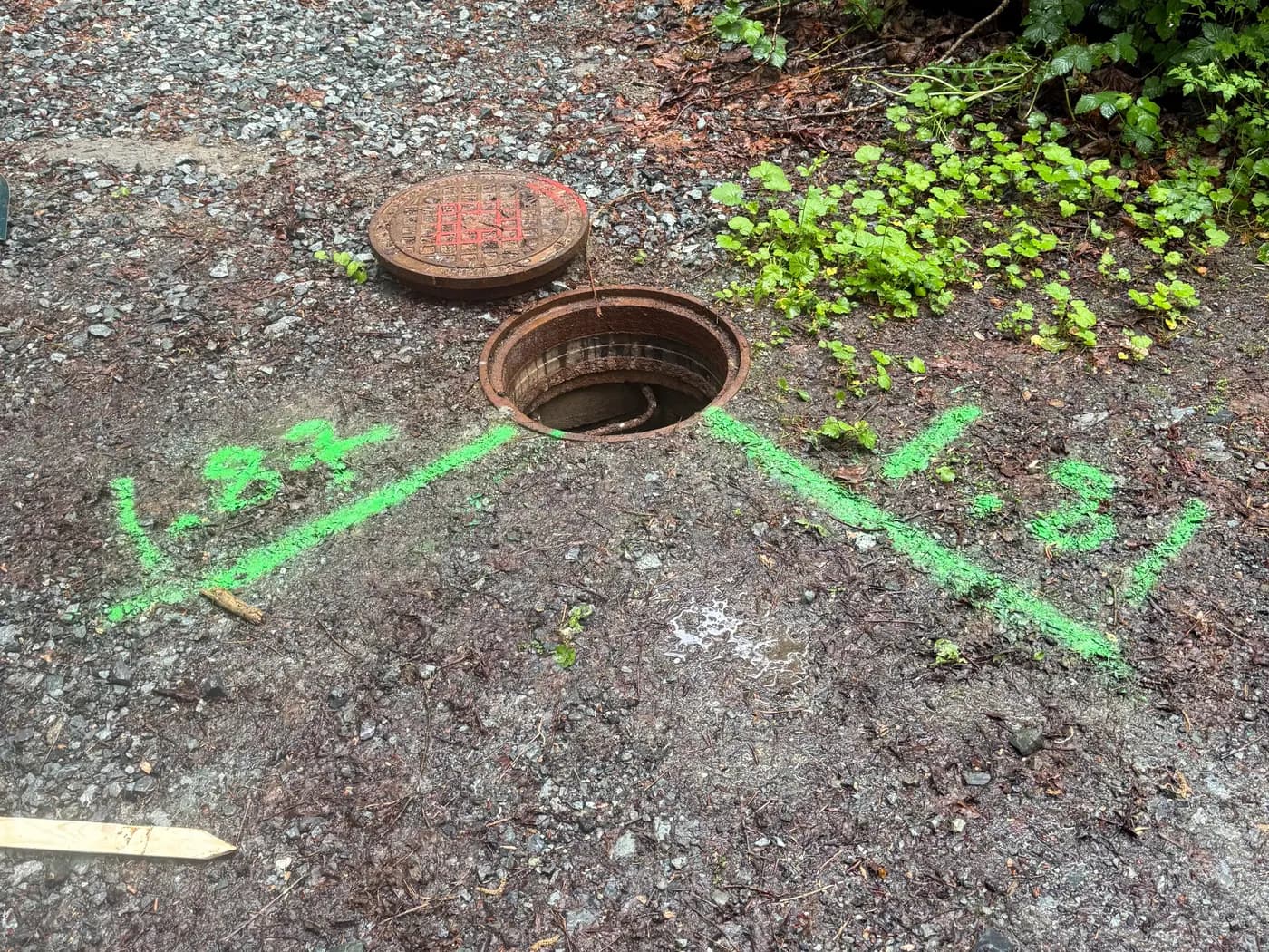 Manhole lids at grade with survey paint marks recording as-built measurements