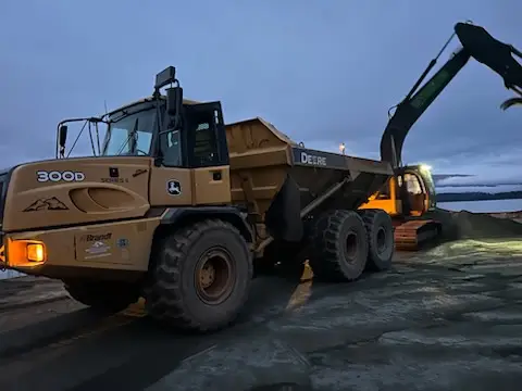Excavator loading an articulated rock truck with structural fill on a BC site development