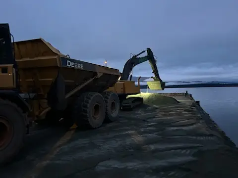 Rock truck and excavator placing material on a shoreline jetty