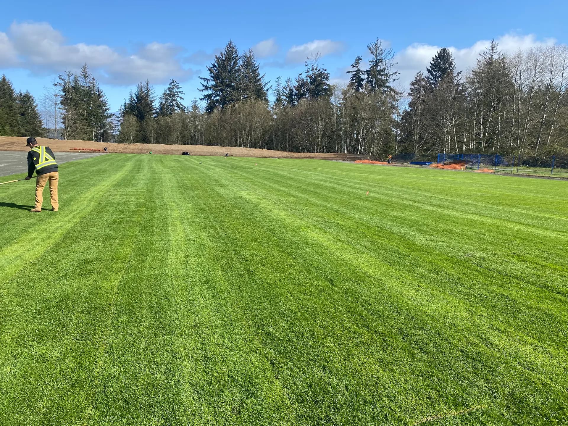 Crew members installing big-roll sod on a community sports field