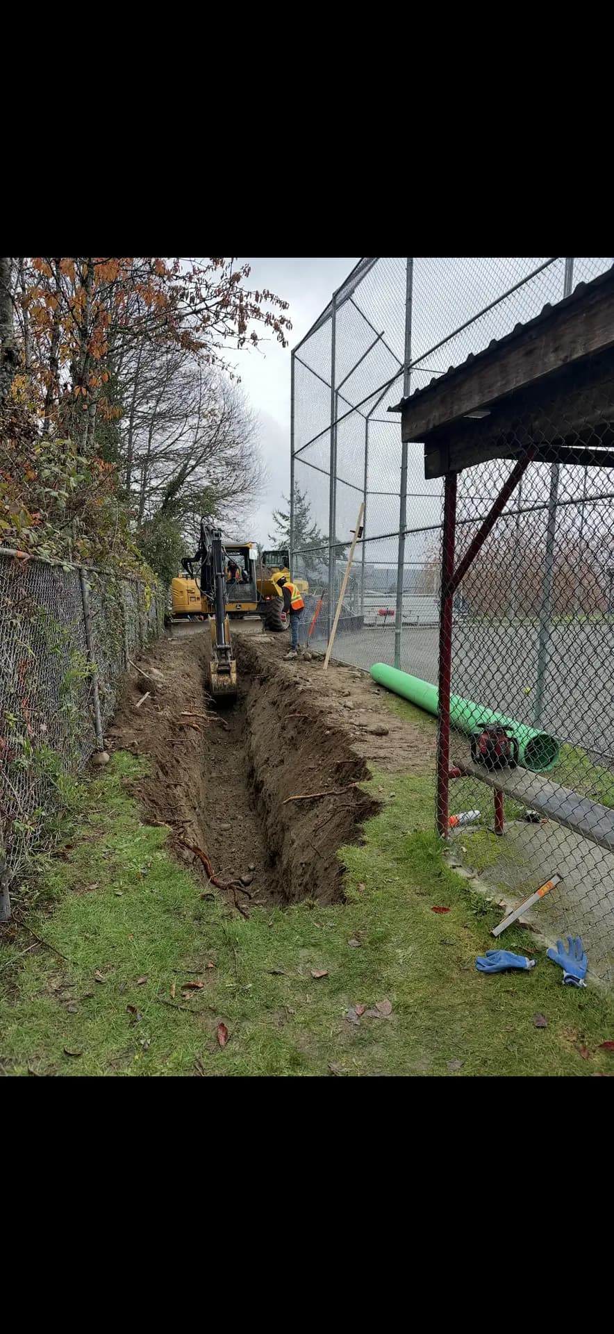 Excavator digging a utility trench with pipe ready for install